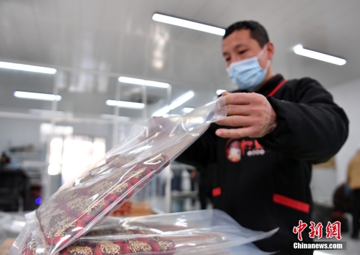 1月18日，雄安新區(qū)大樹劉莊村辛愛青家中的冰糖葫蘆加工廠，工人正對冰糖葫蘆半成品進行真空塑封。作為遠近聞名的“冰糖葫蘆村”，大樹劉莊村制作冰糖葫蘆的歷史已有100多年，全村三分之二的村民都會這門手藝，吸引不少游客慕名而來。 中新社記者 韓冰 攝
